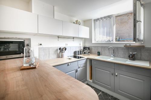 une cuisine avec des armoires blanches et un comptoir en bois dans l'établissement L'échappatoire - A 300 m de la plage, à Bernières-sur-Mer