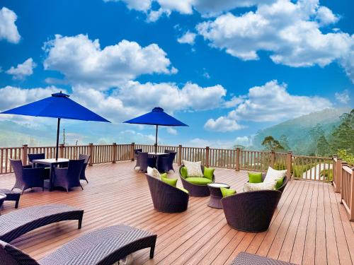 a deck with chairs and tables and blue umbrellas at Hilldale Retreat in Nuwara Eliya