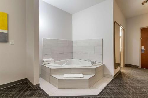 a white bathroom with a tub in a room at Comfort Suites Natchitoches in Natchitoches