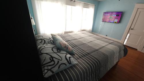 a bedroom with a bed with a striped blanket and a window at Huge 4-Bedroom Historic Home & Game Room in Goldsboro