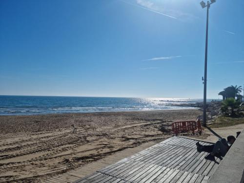 a person sitting on a bench on the beach at RELAX-Apt in Benicarló