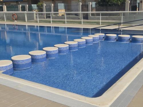 a swimming pool with blue water and white stools at RELAX-Apt in Benicarló