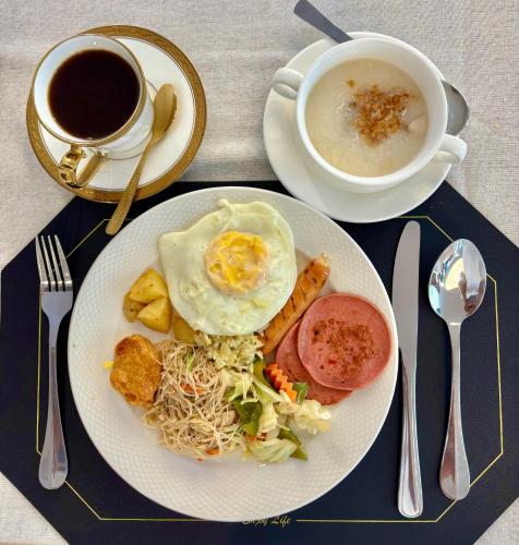 a plate of food with eggs and a cup of coffee at Klassique Sukhumvit Hotel in Bangkok