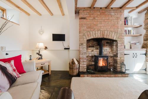 ein Wohnzimmer mit Kamin und Couch in der Unterkunft Sweetheart Cottage - Cosy 2 Bed in The Cotswolds! in Swalcliffe