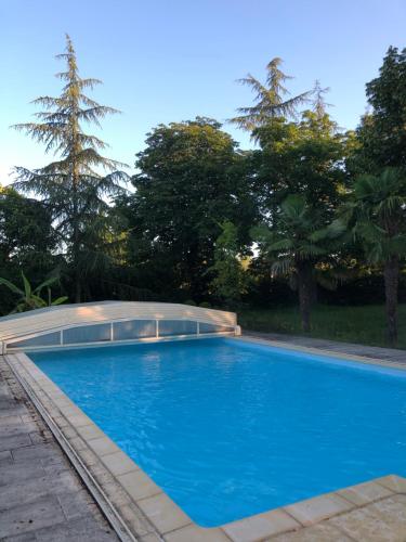 une piscine bleue avec des arbres en arrière-plan dans l'établissement Périgourdine avec piscine, nature & bastides, à Faux