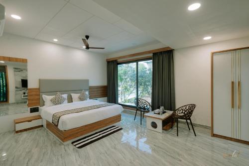 萨三吉尔Daksh Eden Greenz -A Luxury Resort in Sasan Gir的一间带床和大窗户的卧室