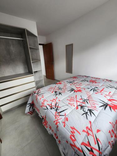a bedroom with a bed with a red and white comforter at Apartamento Vale da Lua, Bezerros in Bezerros