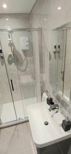 a bathroom with a shower and a white sink at Cullentra House in Cushendall