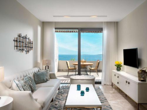 a living room with a couch and a tv and a table at Swissôtel Living Bodrum in Bodrum City