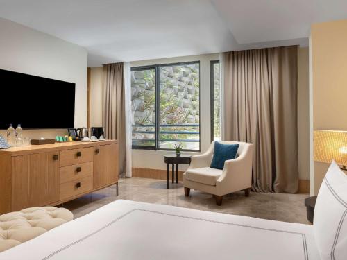 a living room with a tv and a chair at Swissôtel Living Bodrum in Bodrum City