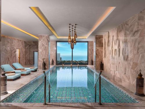 a swimming pool in a room with a stone wall at Swissôtel Living Bodrum in Bodrum City