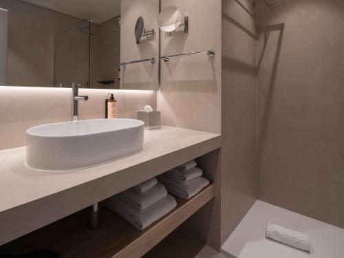 a white bathroom with a sink and a shower at Mercure Ponta Delgada Azores in Ponta Delgada