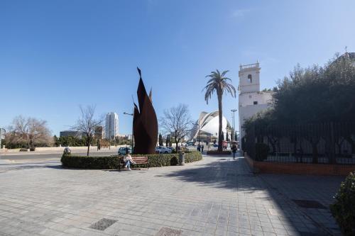 a person sitting on a bench next to a statue at Les Arts Plaza by Concept Flats in Valencia