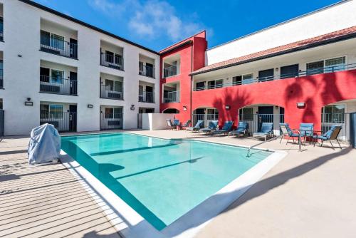 a pool in front of a building with chairs and tables at Quality Inn San Diego South - Chula Vista in Chula Vista