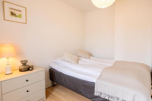 a white bedroom with a bed and a nightstand at Penthouse in the heart of Copenhagen in Copenhagen