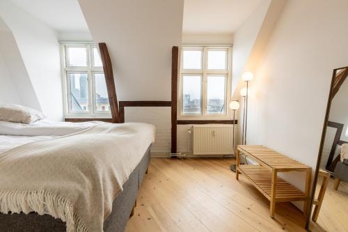 a bedroom with a bed and two windows and a table at Penthouse in the heart of Copenhagen in Copenhagen