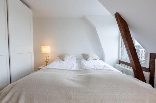 a white bedroom with a large bed and a window at Penthouse in the heart of Copenhagen in Copenhagen