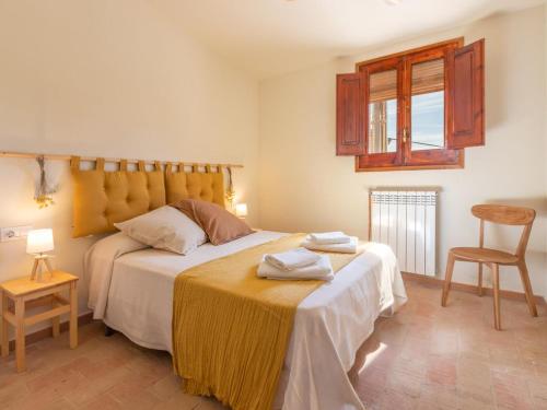 a bedroom with a bed and a chair and a window at Mas Mare de la Font: Els Masovers / 1093 in Castelló d'Empúries