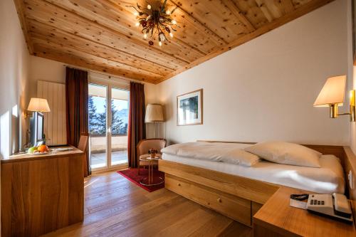 a bedroom with a large bed with a wooden ceiling at Hotel Prätschli in Arosa