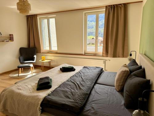 a bedroom with a couch and a chair and windows at Spacious, stylish & central apartment, Great excursions in surrounding area in Meiringen