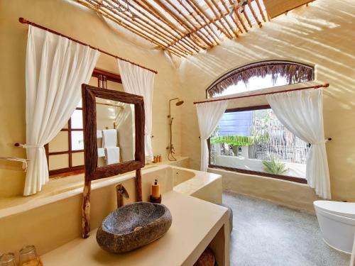 a bathroom with a mirror and a tub and a sink at Red Sands Mui Ne in Phan Thiet