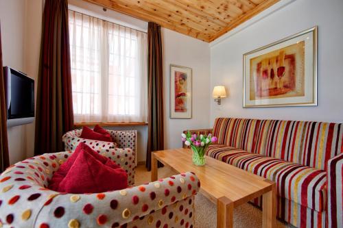 a living room with a couch and a table at Hotel Prätschli in Arosa