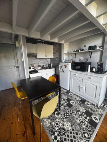 une cuisine avec une table noire et des chaises jaunes dans l'établissement Appartement Royat 2 pièces 33m2, à Royat