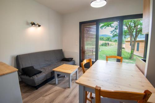 un salon avec un canapé et une table dans l'établissement Chalet 4 personnes - camping les berges du bramont, à Saint-Beauzile
