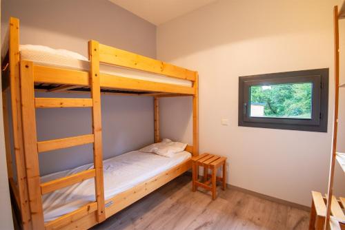 une chambre avec deux lits superposés et une fenêtre dans l'établissement Chalet 4 personnes - camping les berges du bramont, à Saint-Beauzile