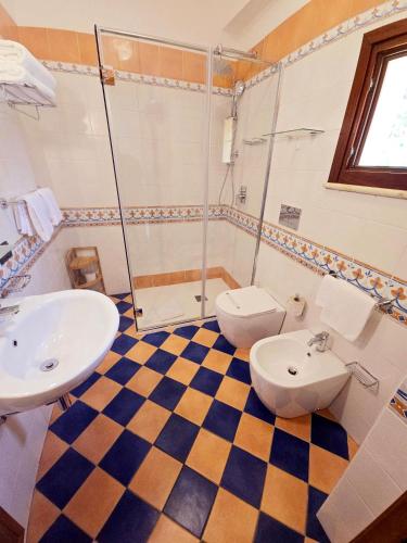 a bathroom with two sinks and a shower and a toilet at Hotel Cala Marina in Castellammare del Golfo