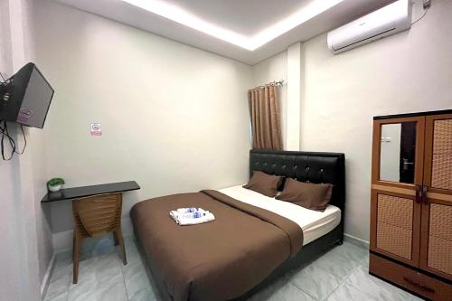 une chambre avec un lit, un bureau et une télévision dans l'établissement Gratia Guesthouse, à Jambi