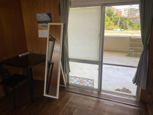 a room with a glass door with a desk and a window at Body Balance House in Miyako Island