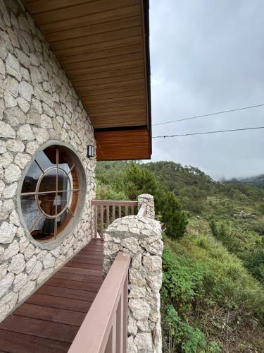a stone house with a wooden porch and a window at ELVEN VILLAS of the The Shire in Sagada