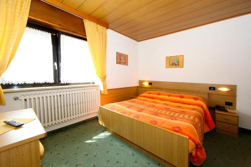 a bedroom with a bed with an orange bedspread at Albergo Venezia in Passo Rolle