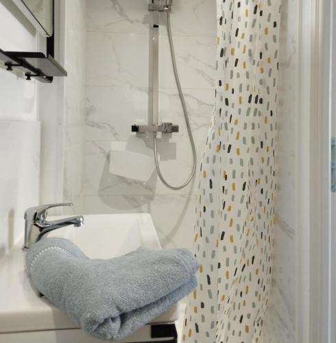 a bathroom with a shower and a towel on a sink at Trois Studios-Cosy centre village in Brouckerque