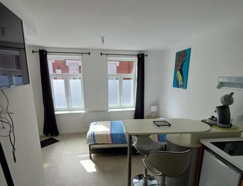 a small kitchen with a table and two windows at Trois Studios-Cosy centre village in Brouckerque