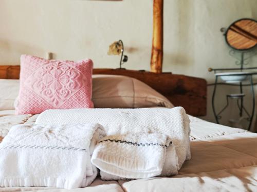 a bed with two white towels and a pink pillow at Affittcamere Jannas in Orgosolo