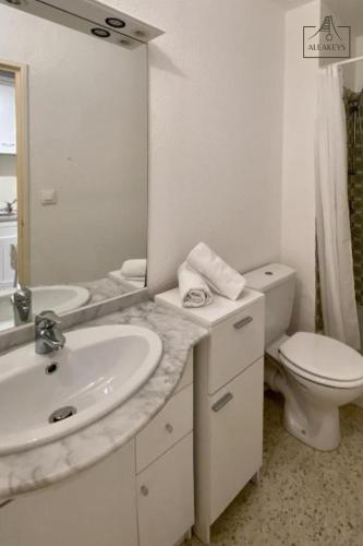 une salle de bain avec un lavabo, des toilettes et un miroir dans l'établissement Studio Le Takeo Quartier Ponant, clim, parking, proche golf, à La Grande Motte