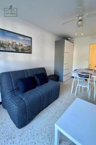 un salon avec un canapé bleu et une table dans l'établissement Studio Le Takeo Quartier Ponant, clim, parking, proche golf, à La Grande Motte