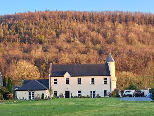 a large white house with a hill in the background at Glangwili Mansion - Luxury 5 star Bed & Breakfast in Carmarthen