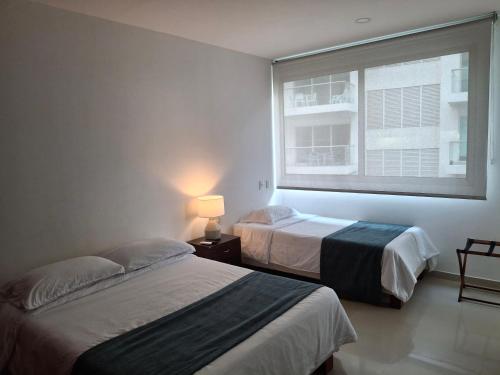 deux lits dans une chambre avec une fenêtre dans l'établissement Cartagena Beach Condo - 1400 sq. Ft. (130 m2), à Carthagène des Indes