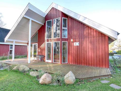 a red house with a wooden deck in the yard at Ferienpark Scharmützelsee in Wendisch Rietz