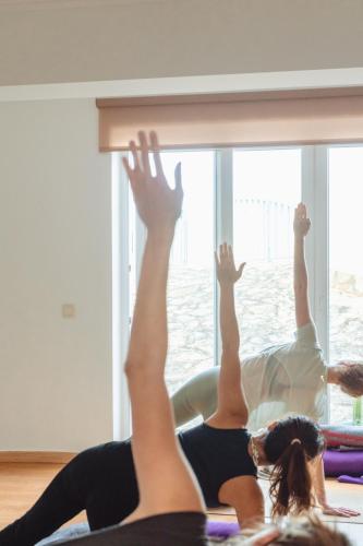 two women laying on the floor with their legs in the air at Surf Yoga Ericeira Guest House in Ericeira
