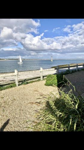 a white sail boat in the water with a fence at Loctudy, les pieds dans l'eau in Loctudy