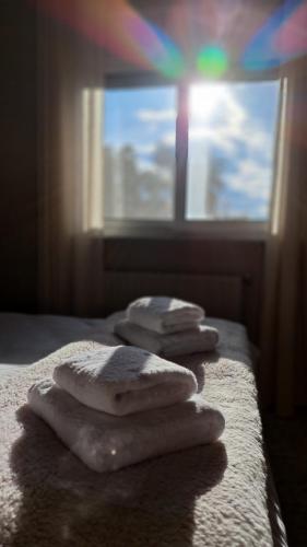 three towels sitting on a bed in front of a window at Albero in Alexandroupoli