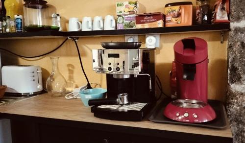 - un comptoir de cuisine avec une cafetière rouge dans l'établissement La Traboule Ponote proche Gr65, au Puy-en-Velay