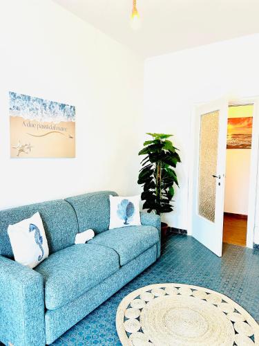 a blue couch in a living room with a plant at Casa vacanza Torvaianica a due passi dal mare in Torvaianica