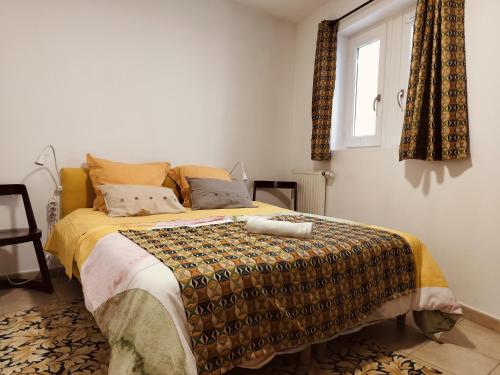 Un dormitorio con una cama en una habitación con ventana. en La Traboule Ponote proche Gr65, en Le Puy en Velay
