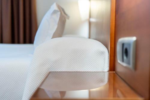 a white chair next to a bed in a hotel room at Nuevo Torreluz in Almería