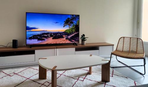 un salon avec une télévision à écran plat sur un mur dans l'établissement L'Atelier Cosy, à Lézignan-Corbières